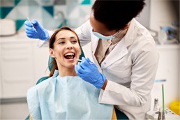 Woman smiling while dentist examines her teeth