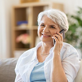 Senior woman sitting on couch talking on phone