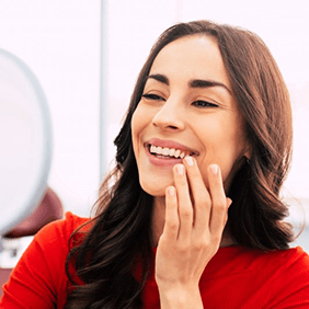 a woman smiling after receiving her dental implant restorations