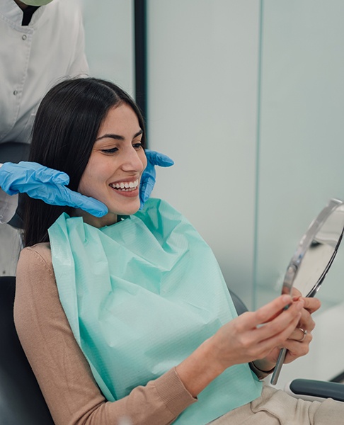 a happy patient admiring her smile in a mirror