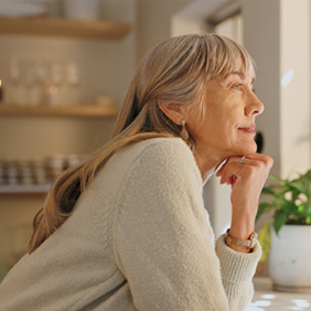 Senior woman smiling while looking out the window at home