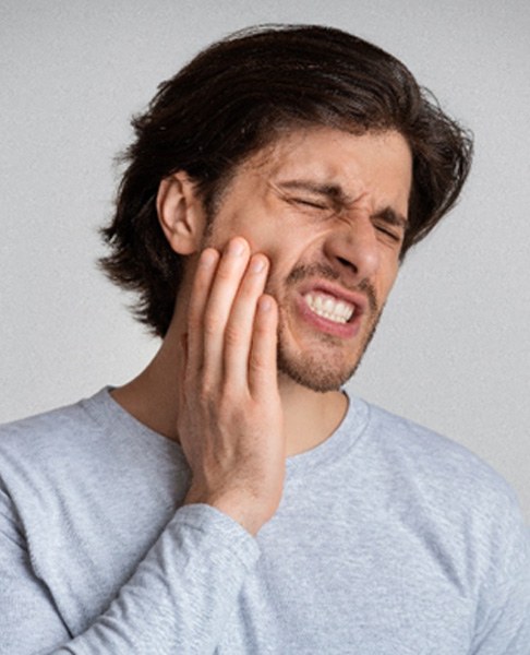 Man with grey shirt suffering from tooth pain