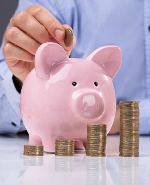 Man putting coins in piggy bank next to model of tooth