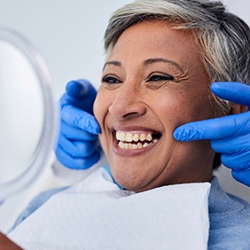 Woman smiling at reflection in handheld mirror