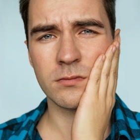 Man with toothache holding cheek in pain