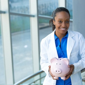 dental professional holding a piggy bank representing making implants affordable
