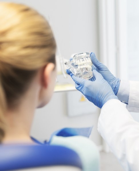 Dentist showing patient a dental implant smile model