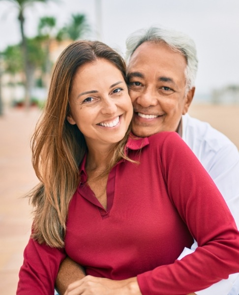 Man and woman smiling after dental implant tooth replacement