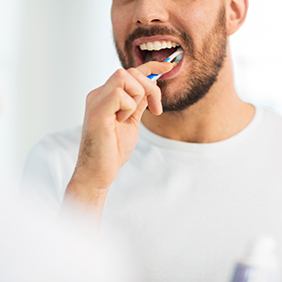 Nose-to-chest view of reflection of man in white shirt brushing teeth