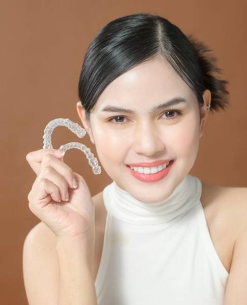 Smiling lady shows off clear aligners