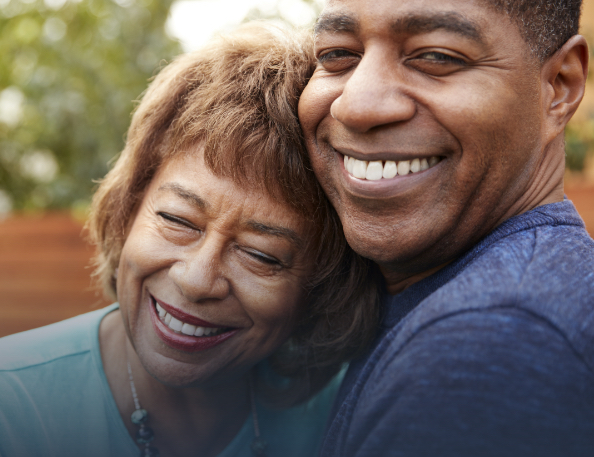 Older man and woman smiling after replacing missing teeth