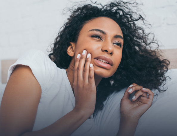 Woman in need of emergency dentistry holding cheek in pain