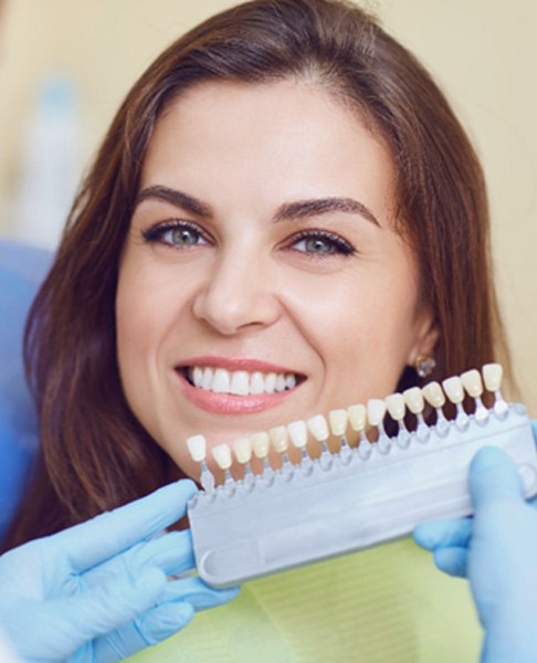 A dentist assessing the shade of a woman’s smile