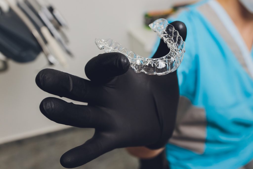 Closeup of dentist holding Invisalign clear aligner