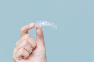 Person holding an Invisalign aligner.